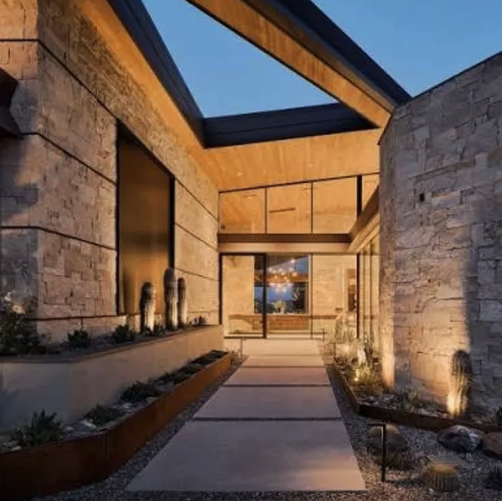 Modern stone estate entrance with a lit walkway at dusk
