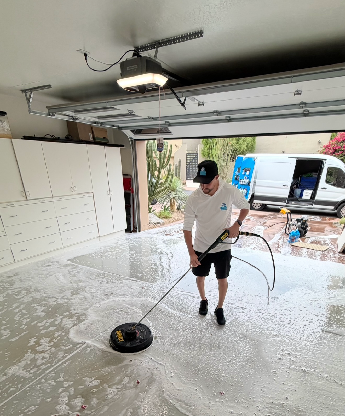Technician deep-cleaning a residential garage floor with a surface cleaner