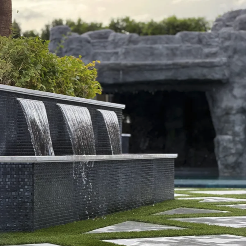 Luxury pool waterfall feature with stone grotto and manicured turf