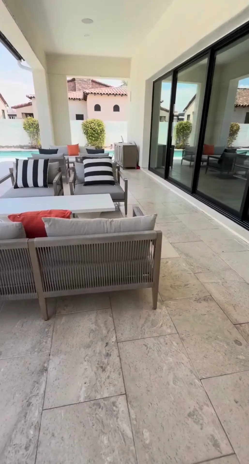 Covered patio with floor-to-ceiling glass doors overlooking a pool